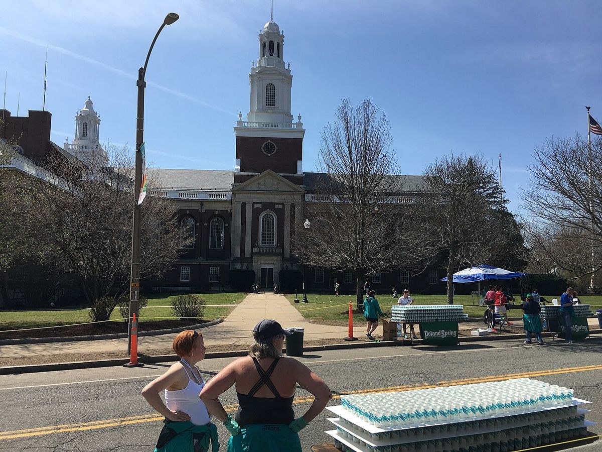 A Boston Marathon water station at Newton City Hall with stacked cups waiting on tables before runners arrive
