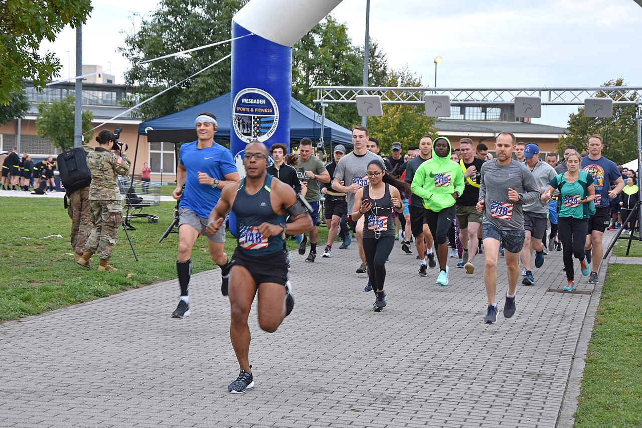 Runners at the start of a community 5K, several in bright neon jackets