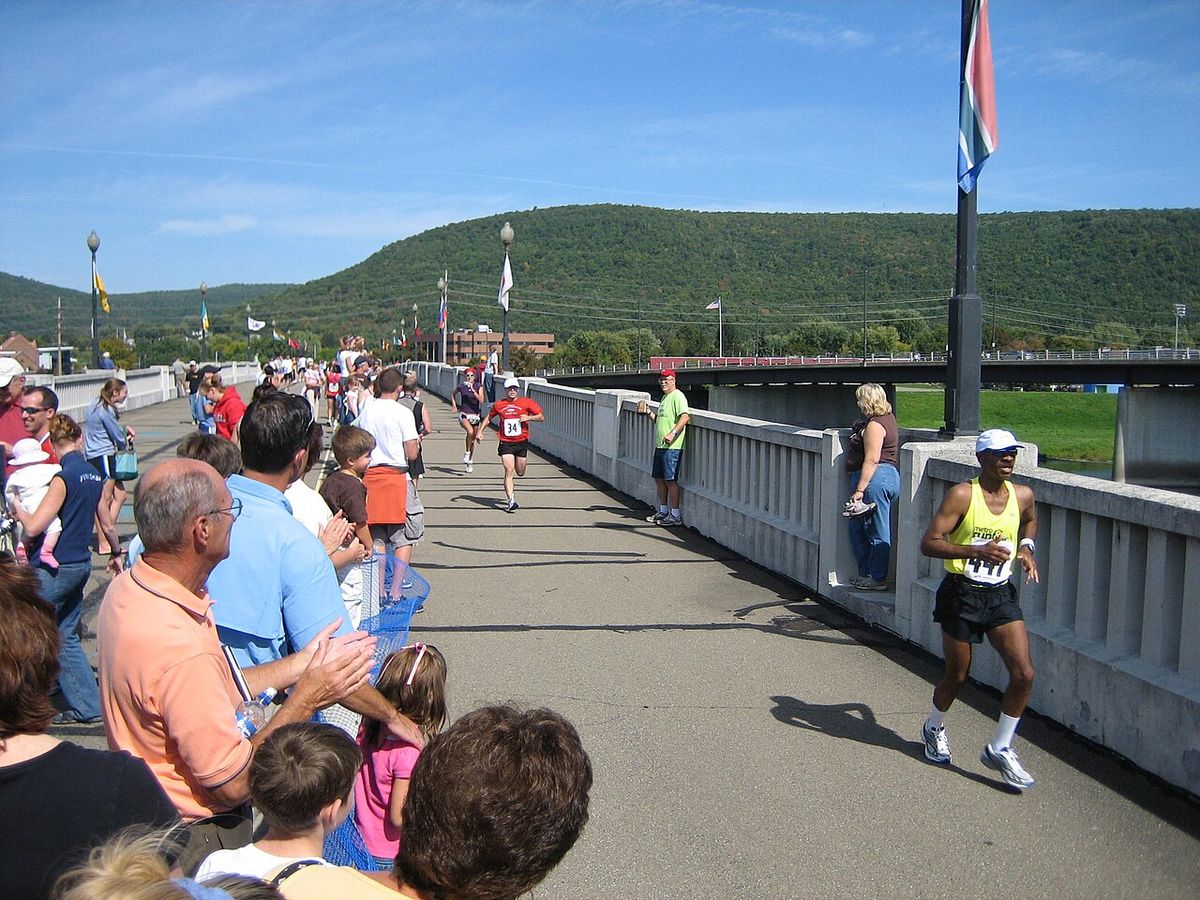 Runners crossing the Wineglass Marathon pedestrian bridge over the Chemung River into Corning as spectators cheer